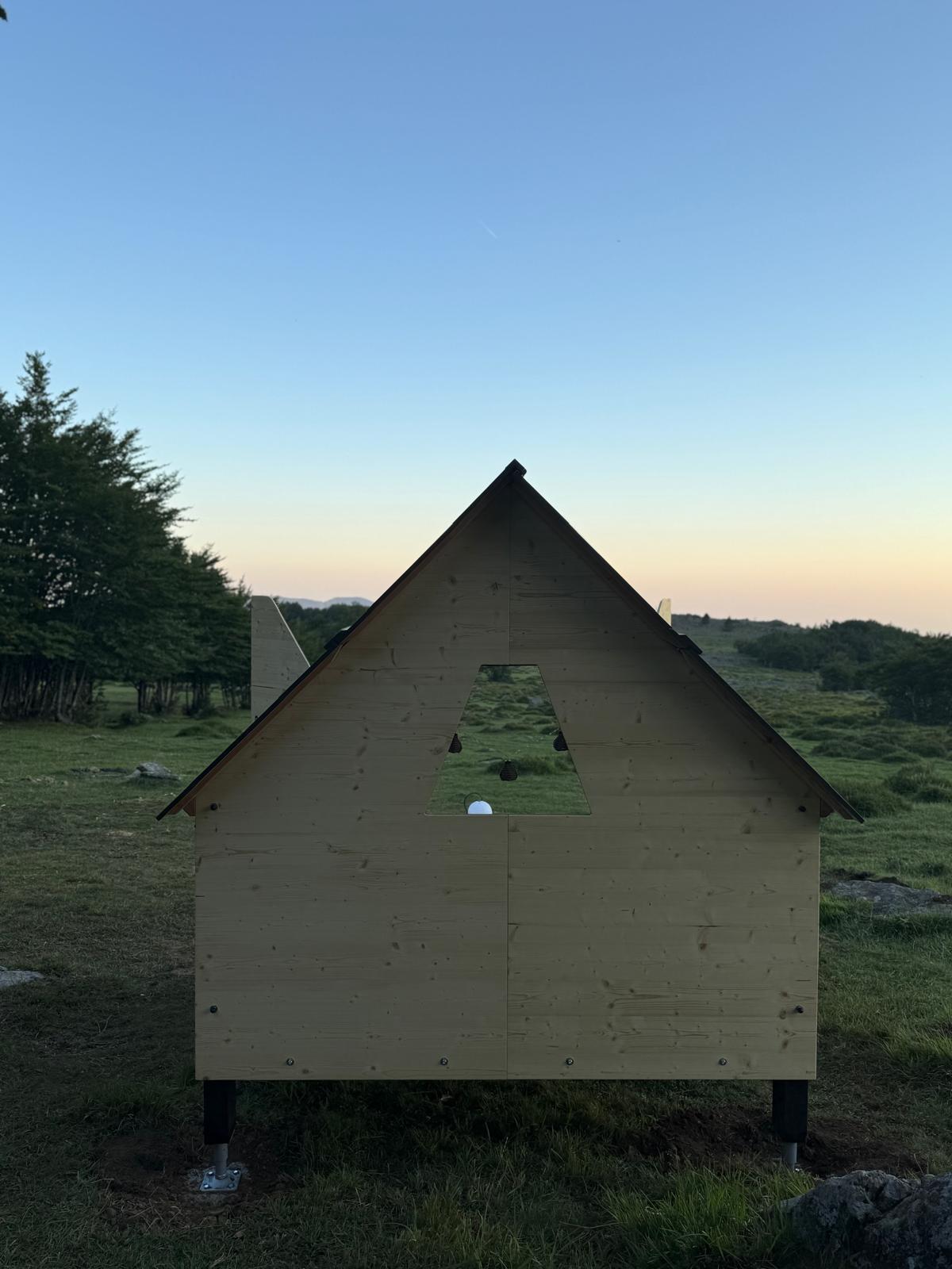 A small cabin with triangular roof at dusk